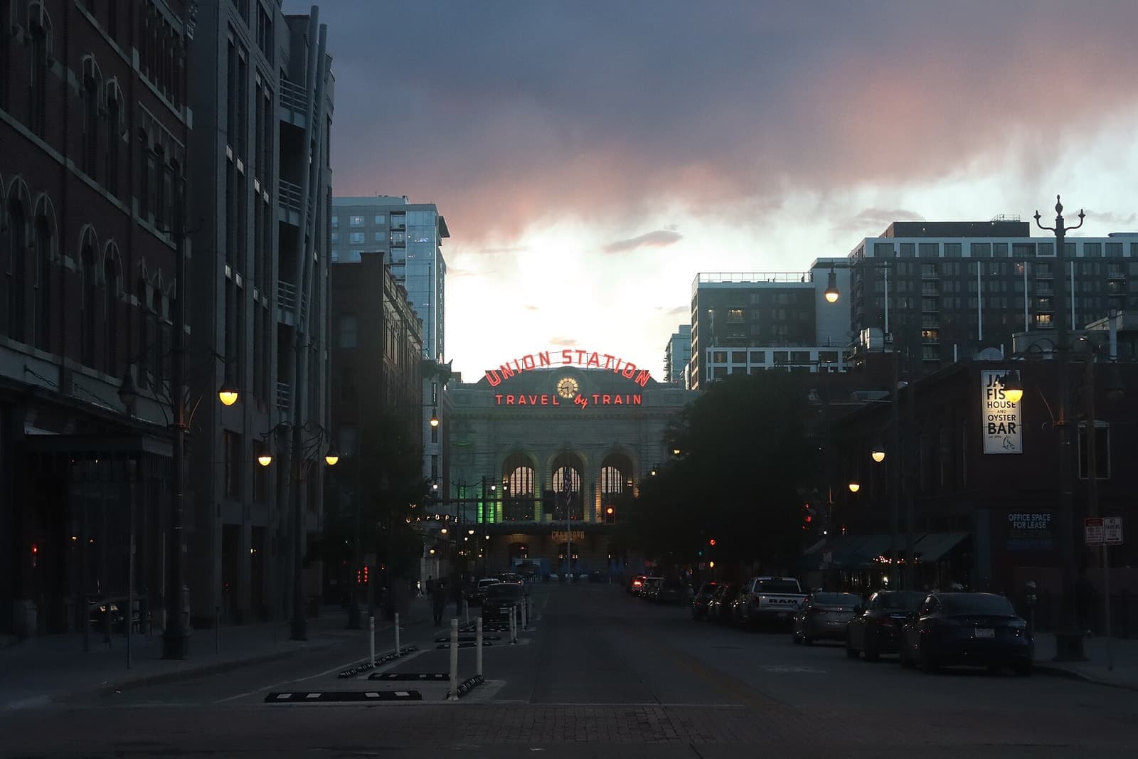 Union Station's Wynkoop facade and Travel by Train sign seen down 17th Street at dusk (2026).